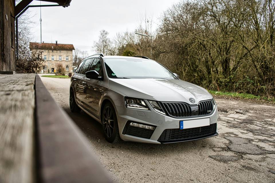 Silver Skoda Octavia estate seen from the front beside a wooden railing