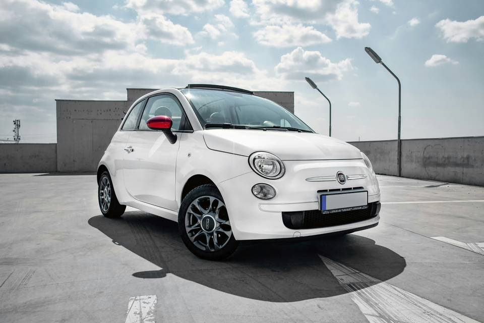 White Fiat 500C with its fabric roof open on a car park roof