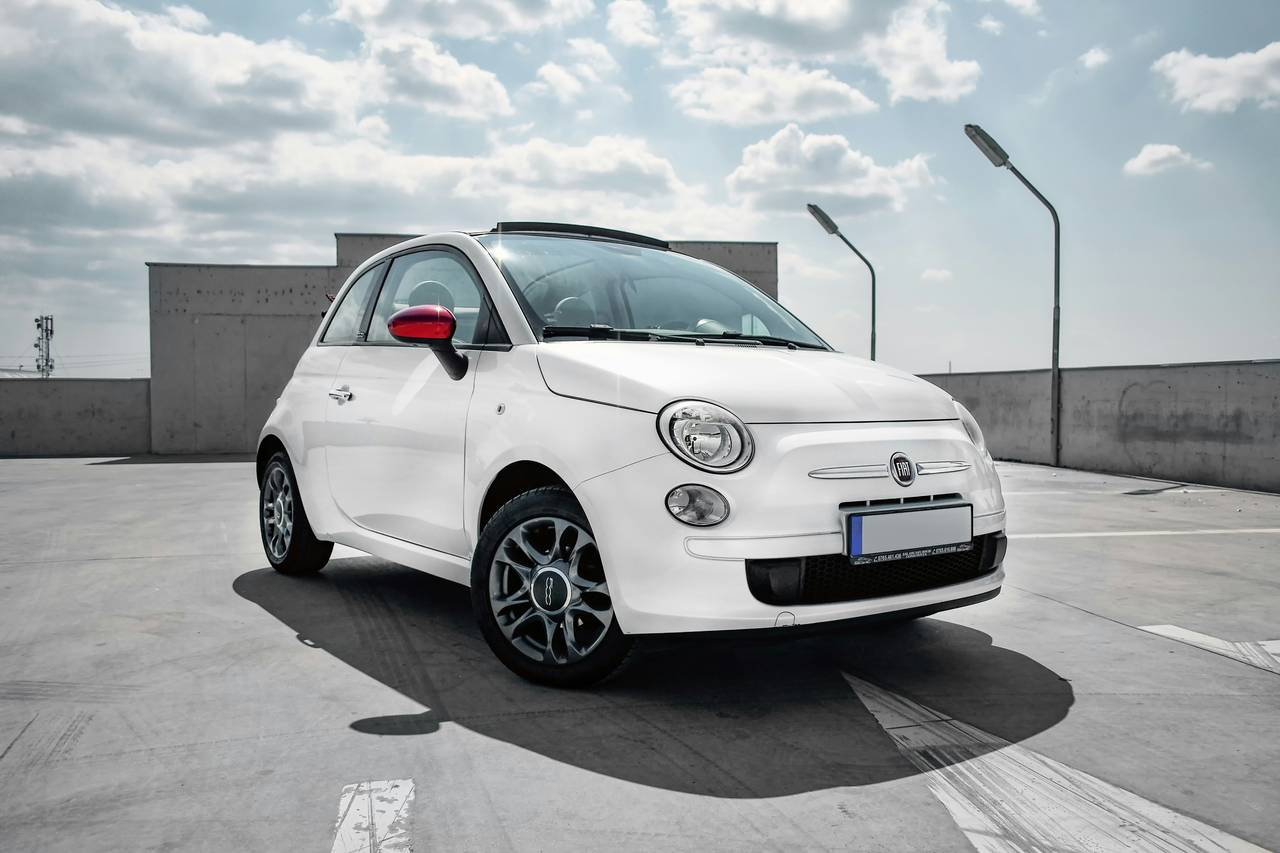 White Fiat 500C with its fabric roof open on a car park roof