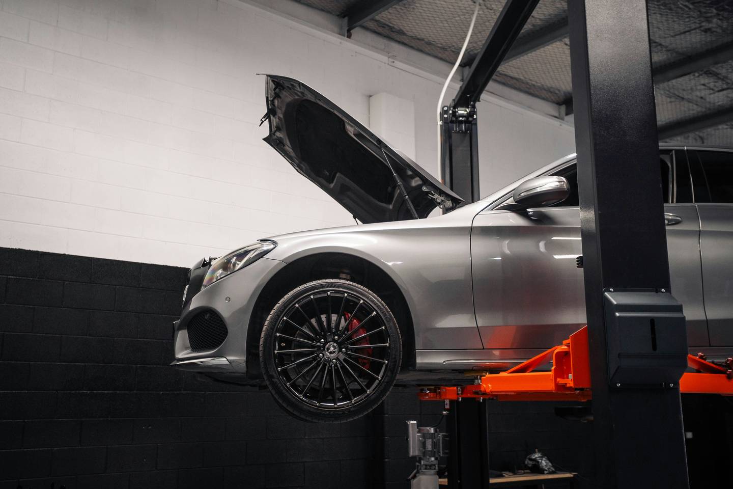 Silver car on a lift in a tidy workshop